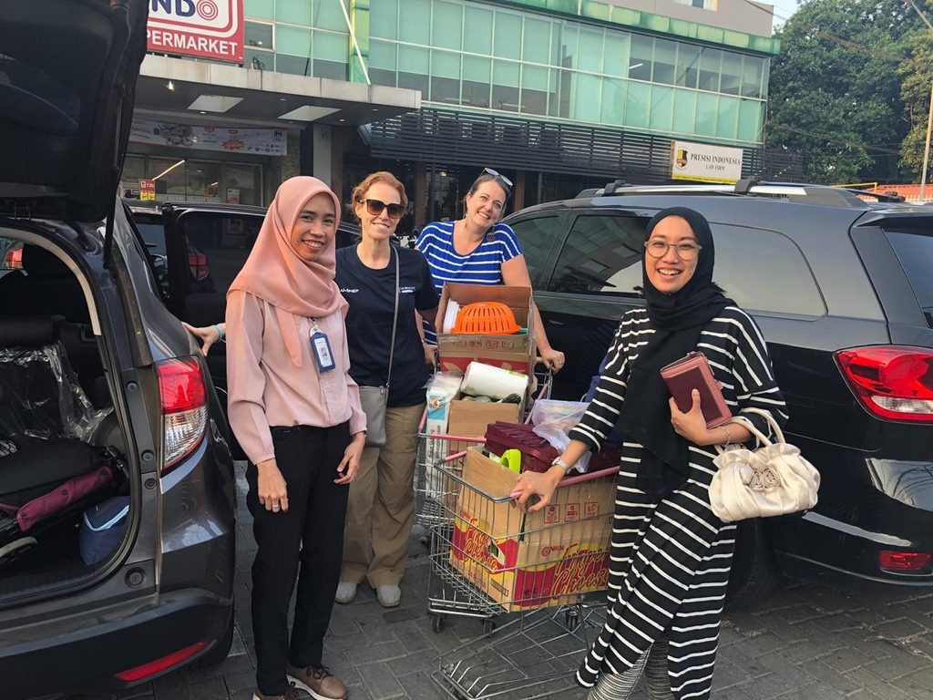 A photo outside of the Super Indo market, showing the store manager, Jayne, Jill, and Lulu with a cart loaded with supplies.